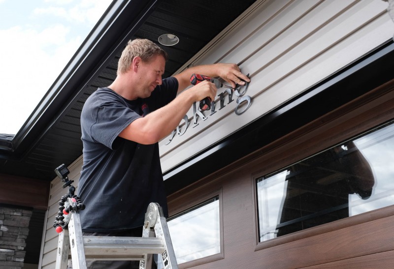 Derek installs signage.