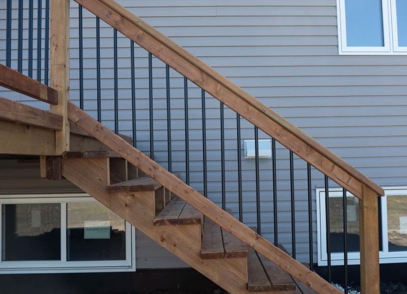 Brown treated stair railing with black ballusters.