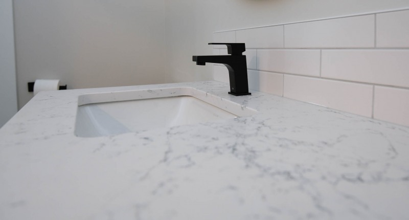 Quartz vanity countertop with undermount sink with black taps.