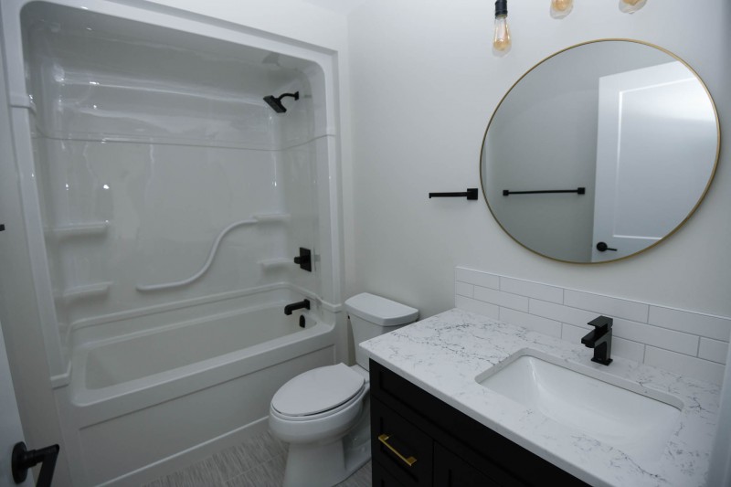 Main bathoom with black plumbing fixtures and gold mirror.